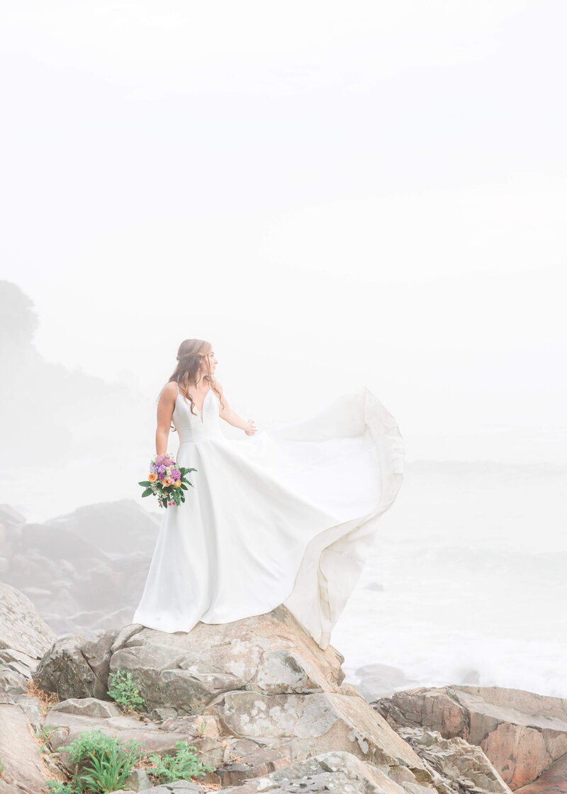 adventurous bride and groom standing on rocks at York Harbor beach for york Inn Wedding  (2)