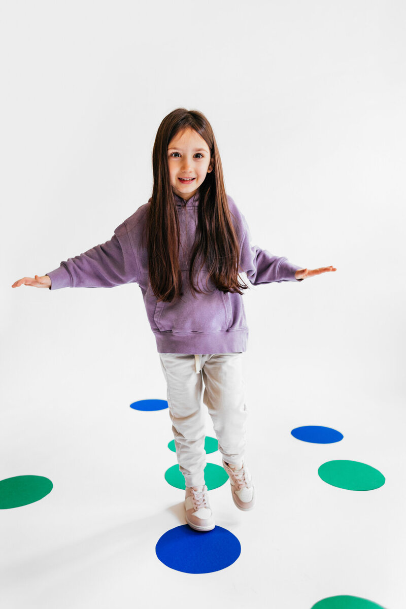 Happy child playing hopscotch on colorful dots