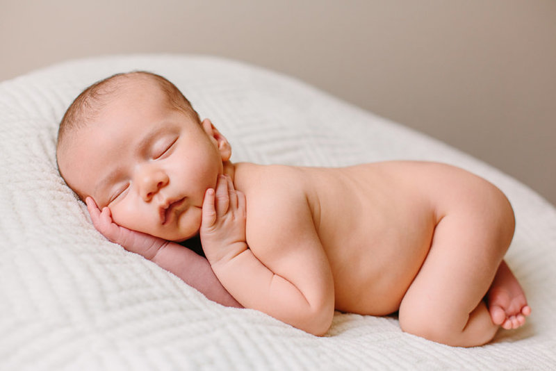 Natural light image of a sleeping newborn baby on a white blanket