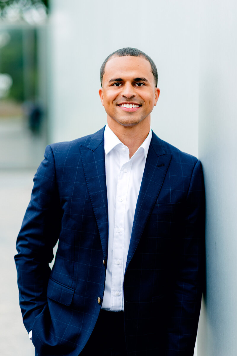 Man smiling for professional headshot leaning against a blue wall