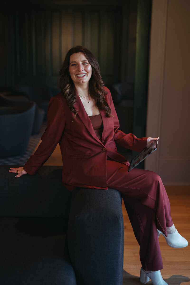 Event planner sitting on counch in a red suit.