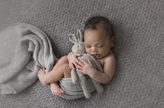 Newborn baby cuddling a stuffed bunny, making for a terrific newborn baby photography setup.