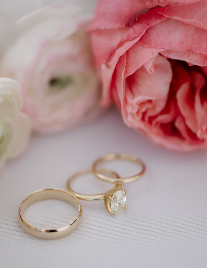 A photo of gold wedding rings and pink roses