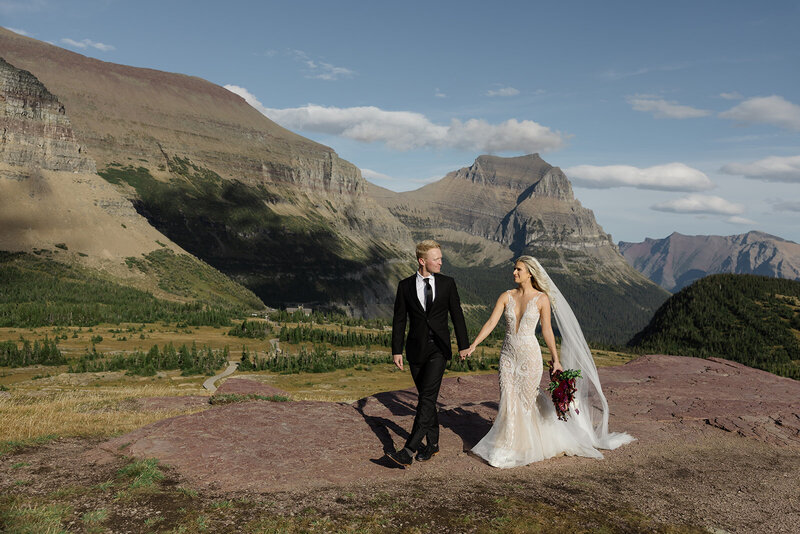 Photo of bride and groom walking across the terrain in Glacier National Park at Logan Pass Visitor Center