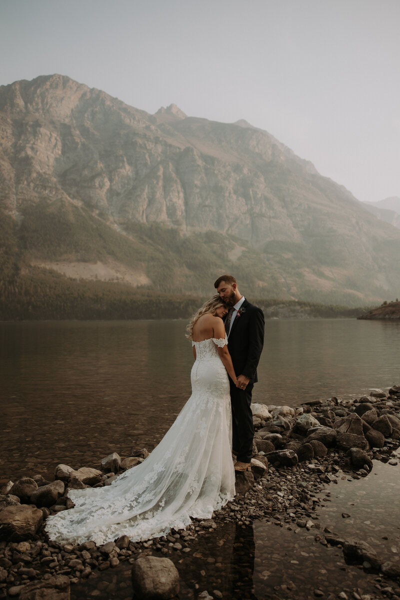 bride and groom standing on lake during an all inclusive elopement day in montana