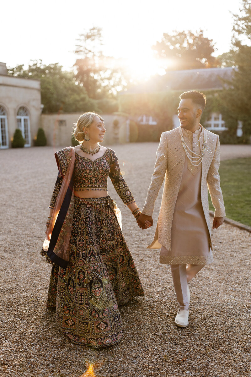 Elegant couple walking through garden for wedding portrait