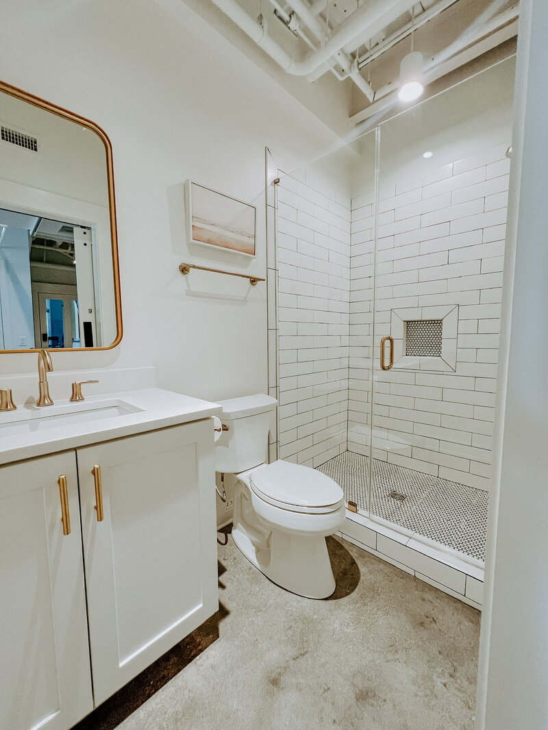 white bathroom with subway tile and gold hardware