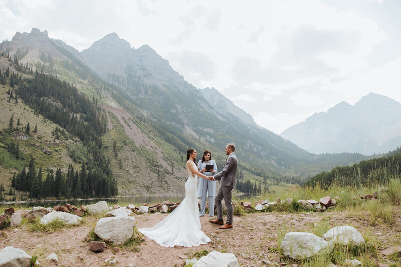 couple saying vows in front of lake in the mountains in colorado