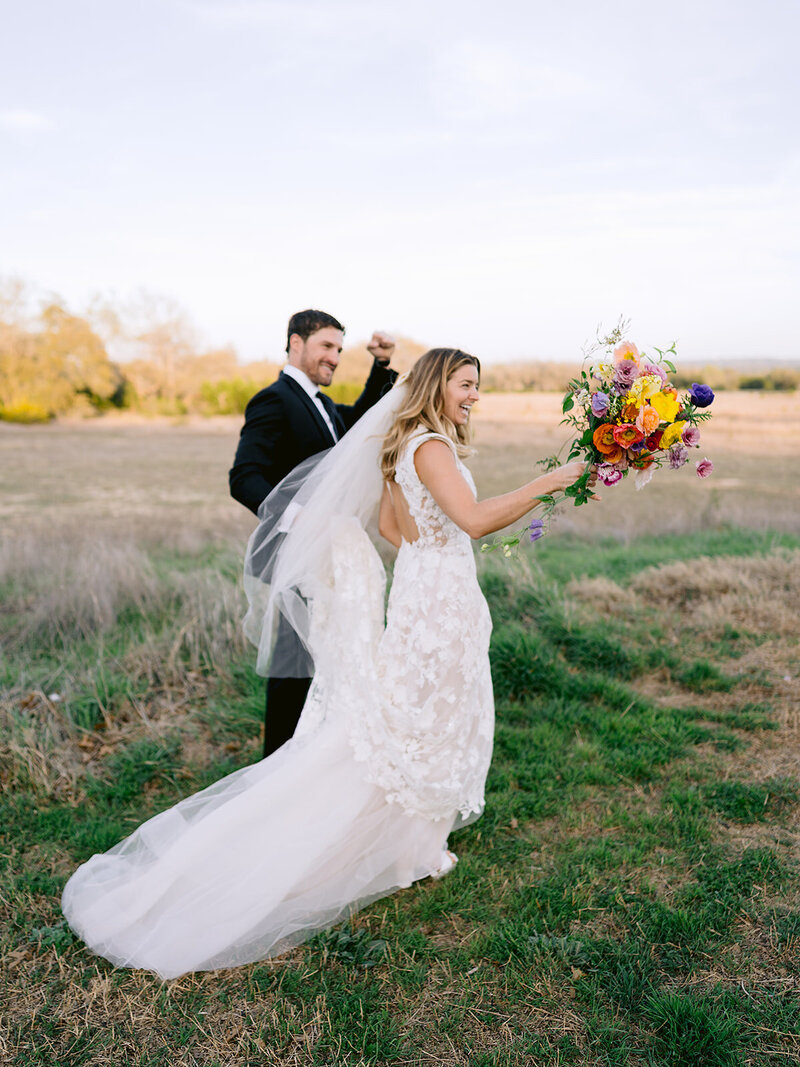 A bride artfully holds a bouquet to obscure her face in a studio portrait