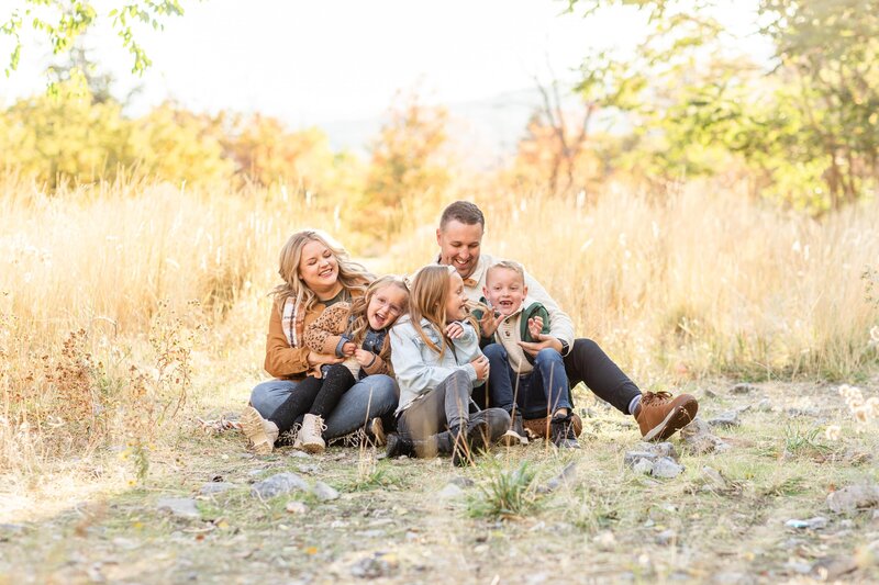 a family sitting together in a field wearing fall colors