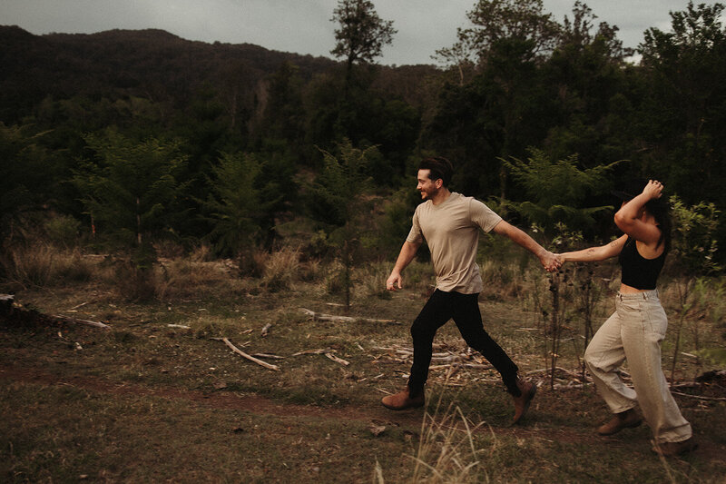 An adventurous couple walking in nature in Brisbane with the male leading the female and holding her hand