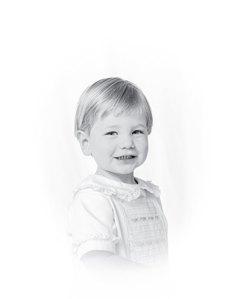 A classic heirloom children's portrait featuring a young toddler with golden hair and bright blue eyes, dressed in a traditional light blue outfit. Timeless children's photography with a soft, painterly background.
