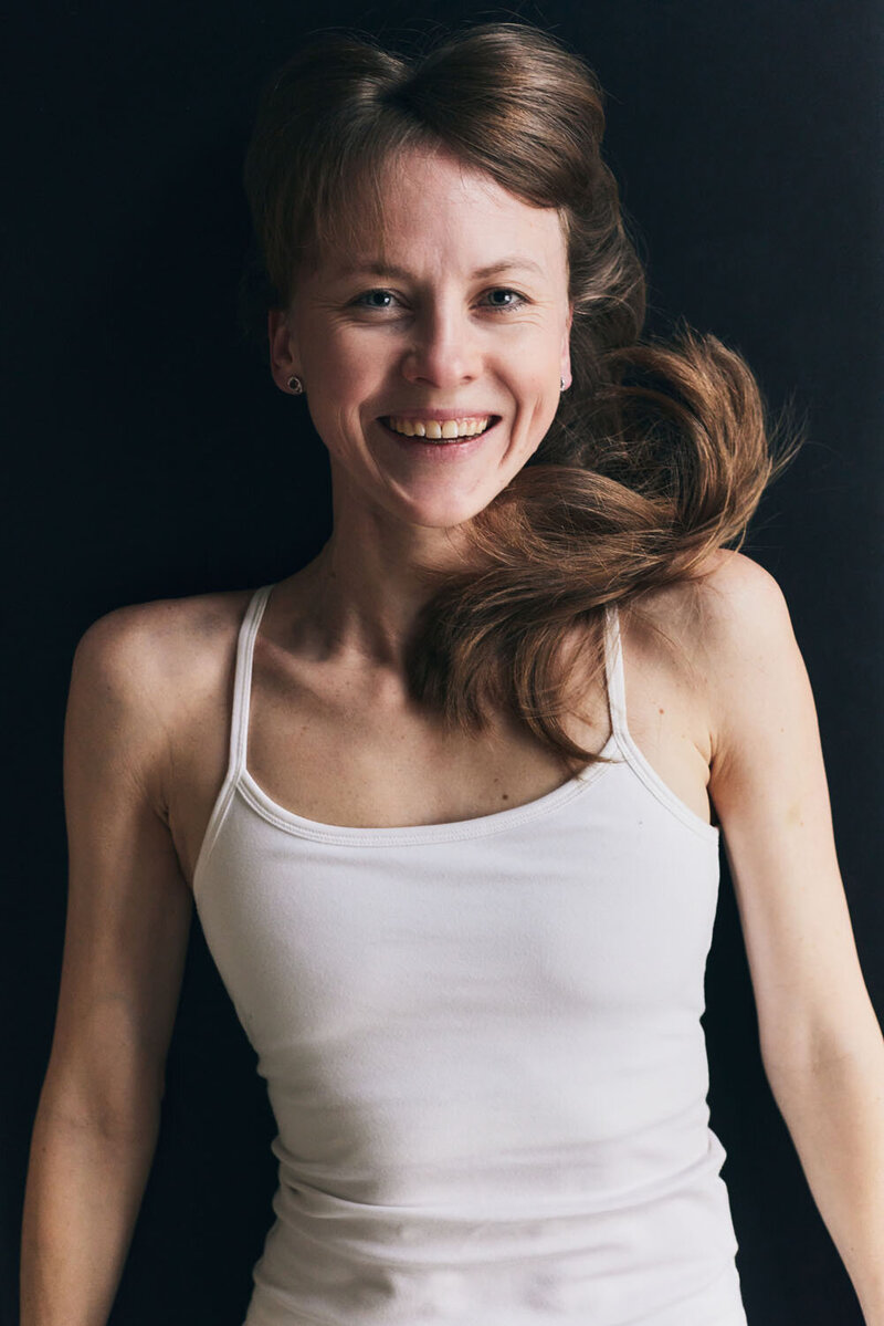 Kasia, a Pilates instructor lying on a performer smiling and looking up at the camera