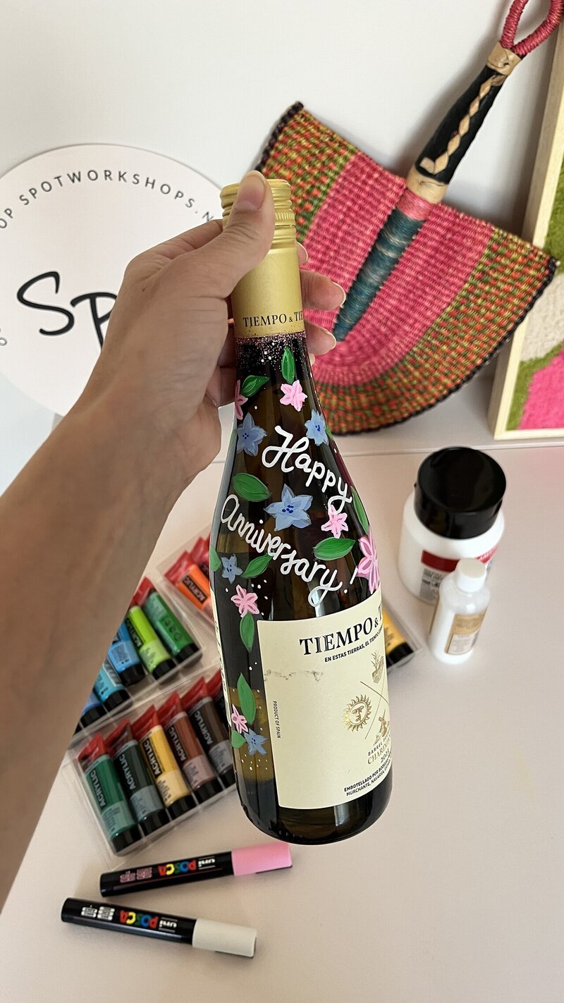 Vrijgezellenfeest workshop, verven van wijnflessen. Hier een voorbeeld met bloemen en tekst geverfd.