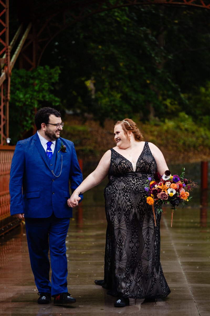 A bride and groom holding hands and walking along the sidewalk