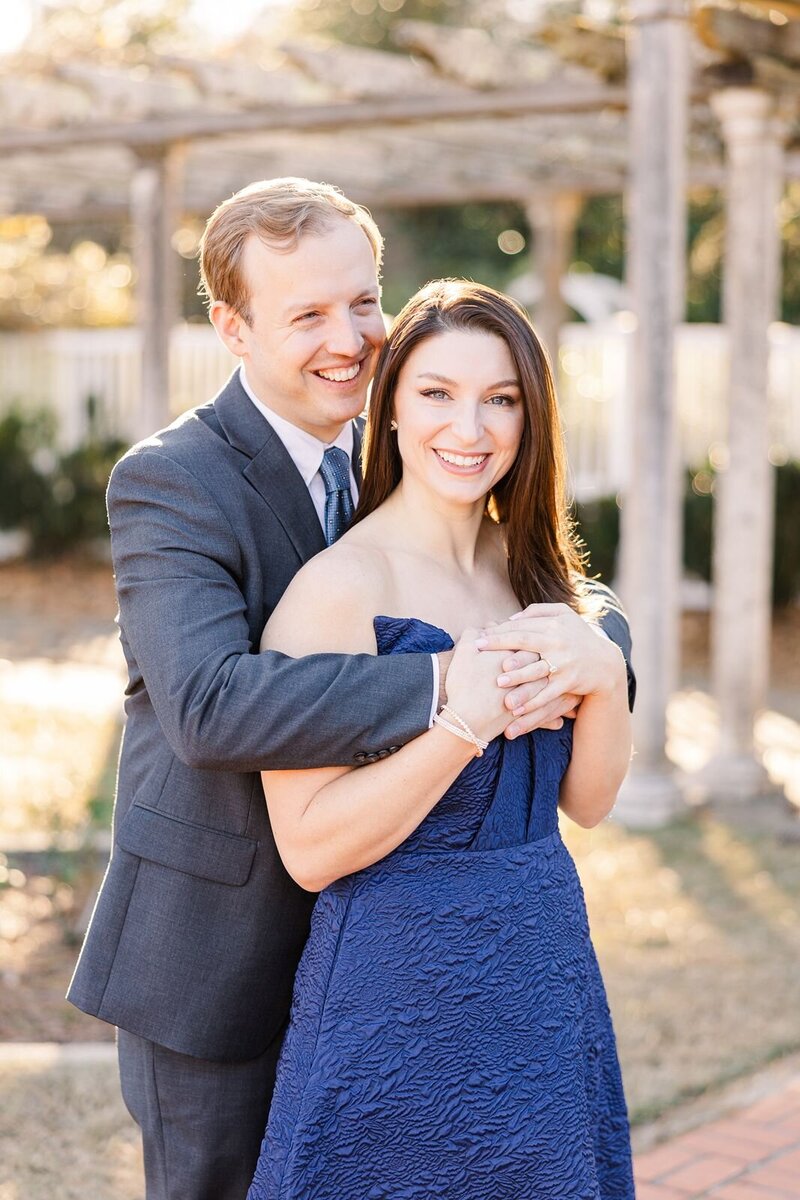 Man embraces his fiance and smiles during engagement portrait session