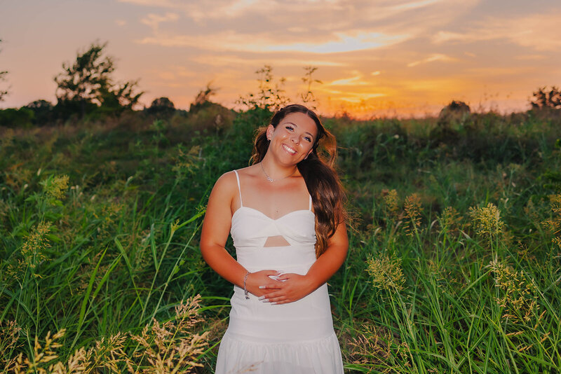 girl posing next to field for senior photos in oklahoma city