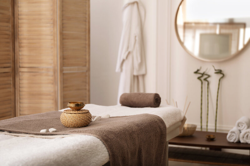Tranquil spa treatment room with a massage table, bamboo decor, and soft natural lighting.
