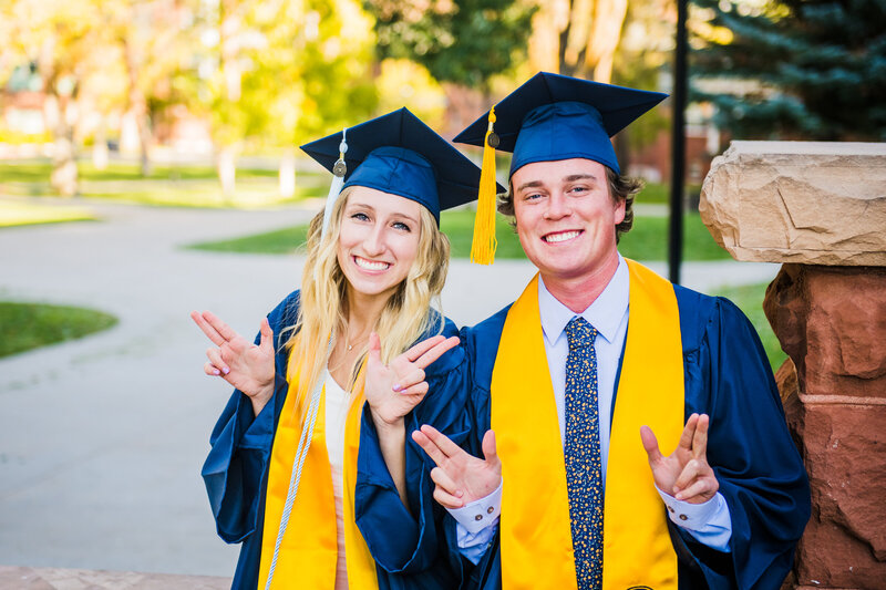 NAU Northern Arizona University couple seniors holding  up LJ wearing caps and gowns at Old Main steps