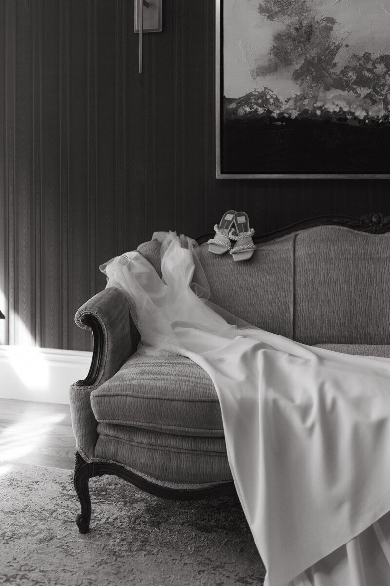Wedding dress and heels elegantly displayed on vintage couch by destination wedding photographer Erica Rochelle Photography