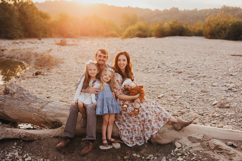 Family photo posing on fallen tree on riverbed