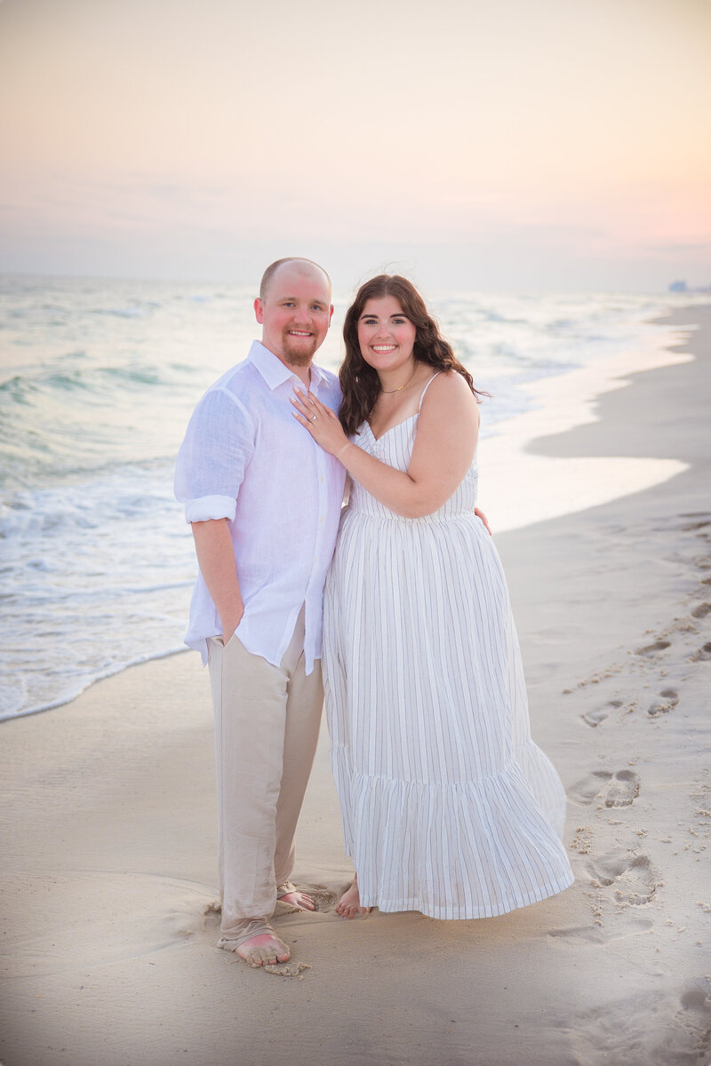 couple standing on shoreline during golden hours