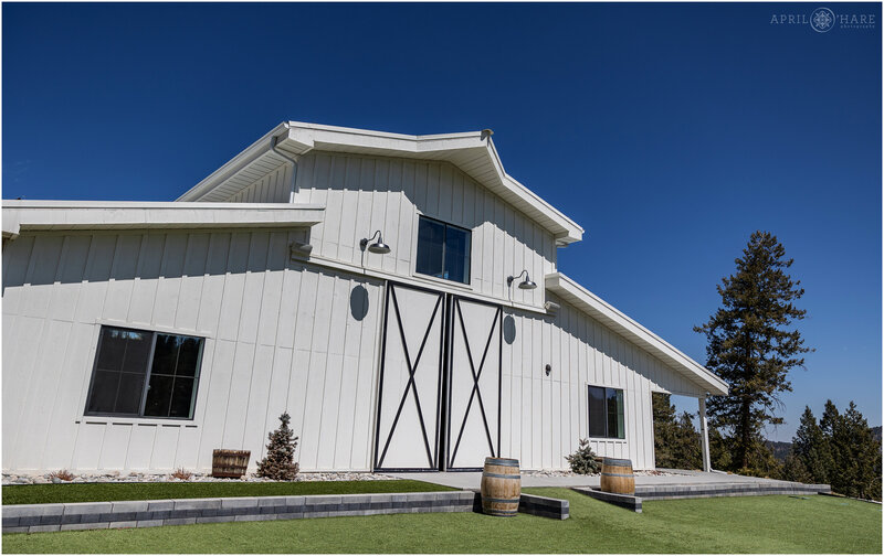 Exterior-of-the-Rear-of-the-White-Barn-from-the-Outdoor-Ceremony-Lawn-at-Woodlands-Wedding-Venue-in-Colorado