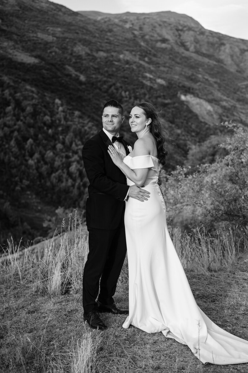 black and white photo of queenstown new zealand mountains with bride and groom in front