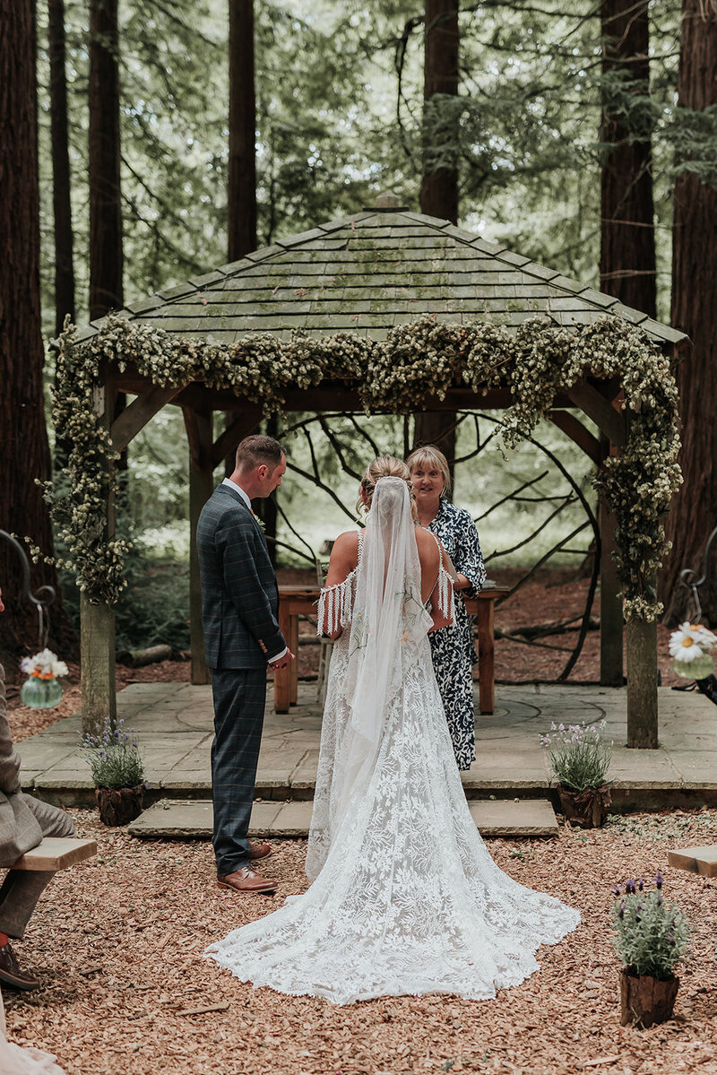 Couple standing in front of a wooden pagoda during their woodland wedding ceremony in the Redwoods at Two Woods Estate, Pulborough