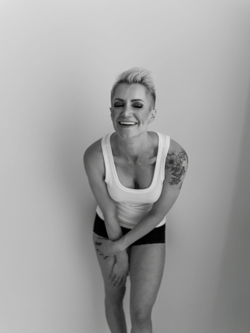 A close-up image of a woman in a white tank top and black underwear, 