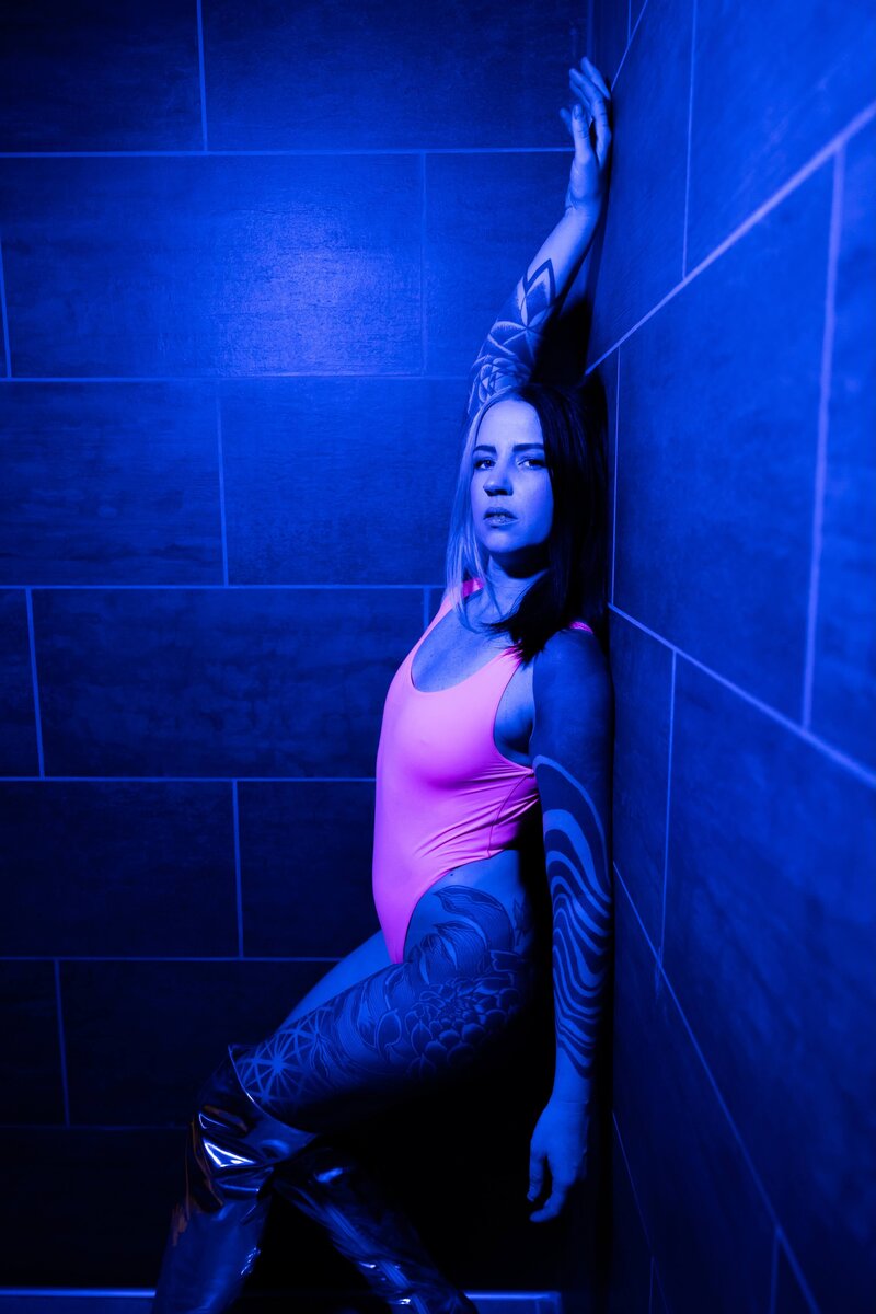 Tattooed Woman in Pink Bodysuit Under Blue Lighting