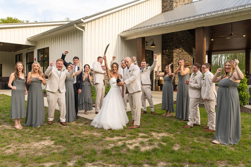 Wedding party cheers as bride and groom pop champagne