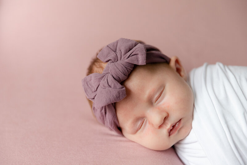 Close up of baby girl sleeping in purple headband at Chicago newborn session by Danielle Hardesty