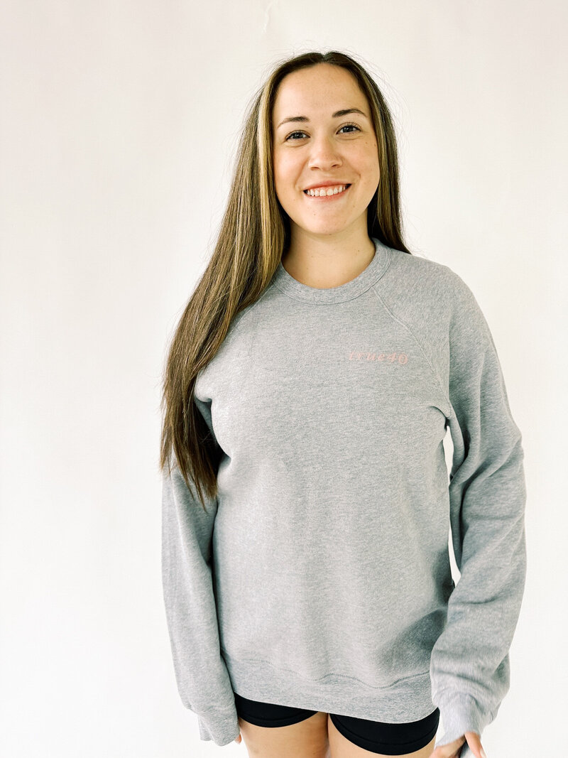 woman wearing gray oversized crewneck with true40 logo on the front