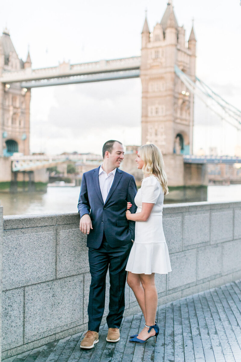 newly engaged couple in front of bridge in london
