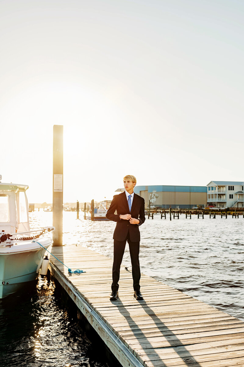 High school senior boy in a  handmade suit at sunset on the dock of the lake in Fort Collins..