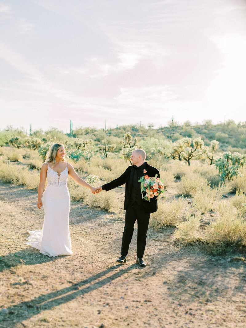 Bride and groom holding hands in the desert