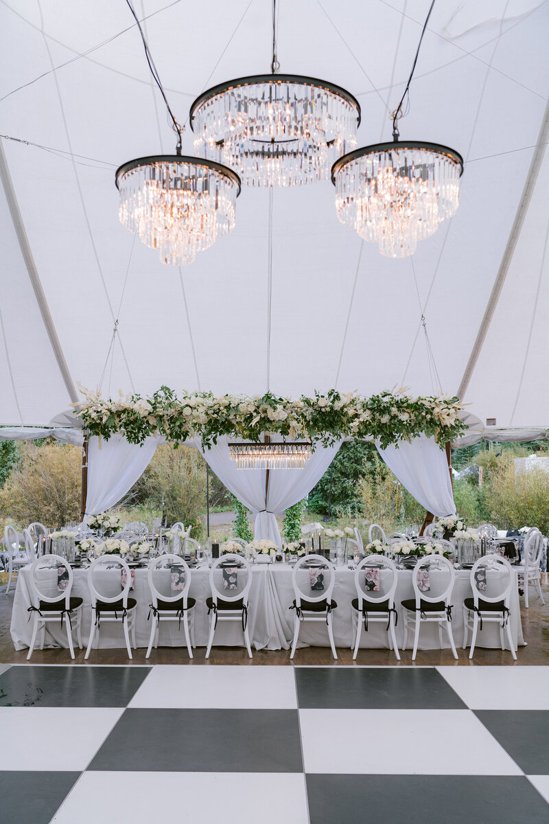 Wedding reception tables in an event tent with chandeliers and custom garlands