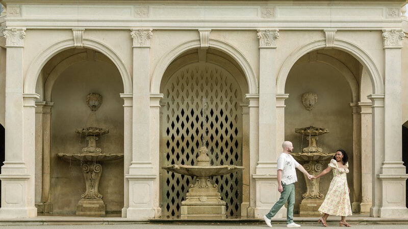 Couple laughing and walking hand-in-hand in the Italian Garden at Longwood Gardens, surrounded by elegant design.