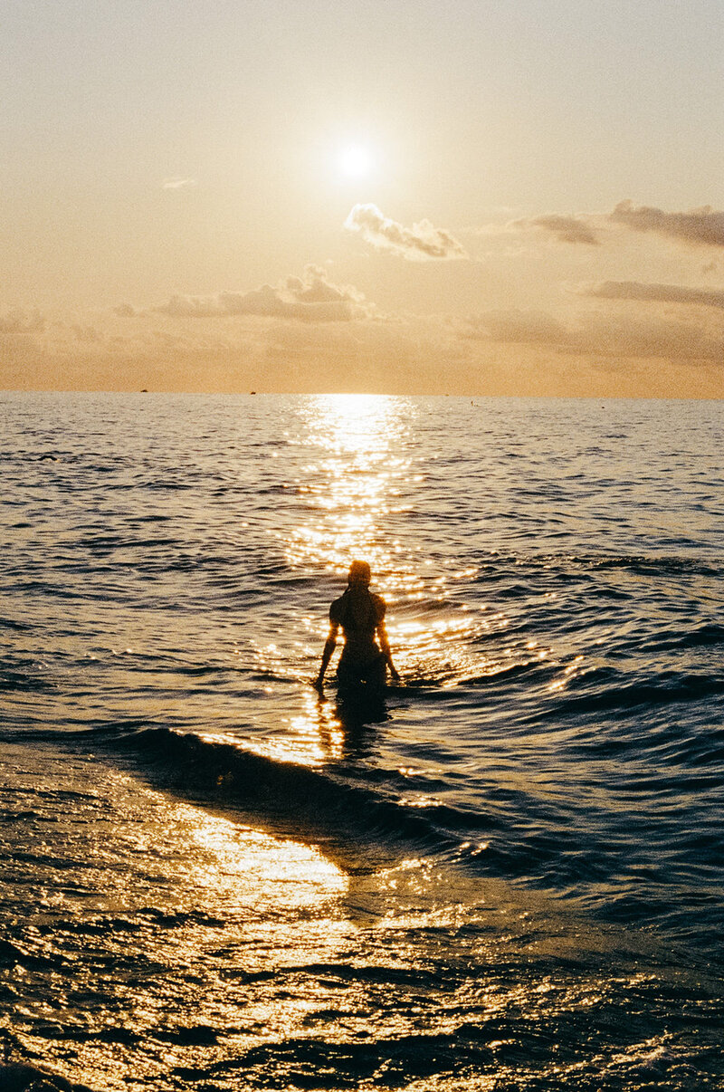 Woman standing in the ocean at sunset