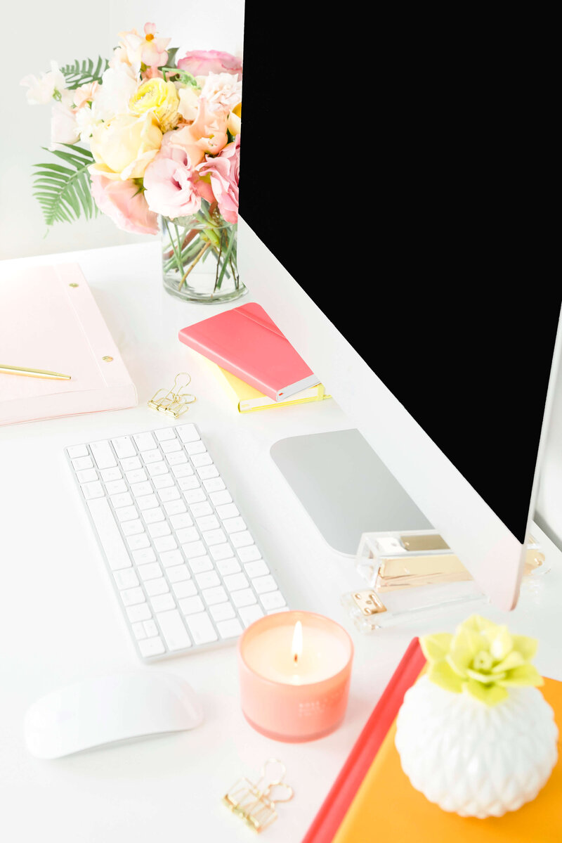 Computer on white desk with bright coral and yellow accents.