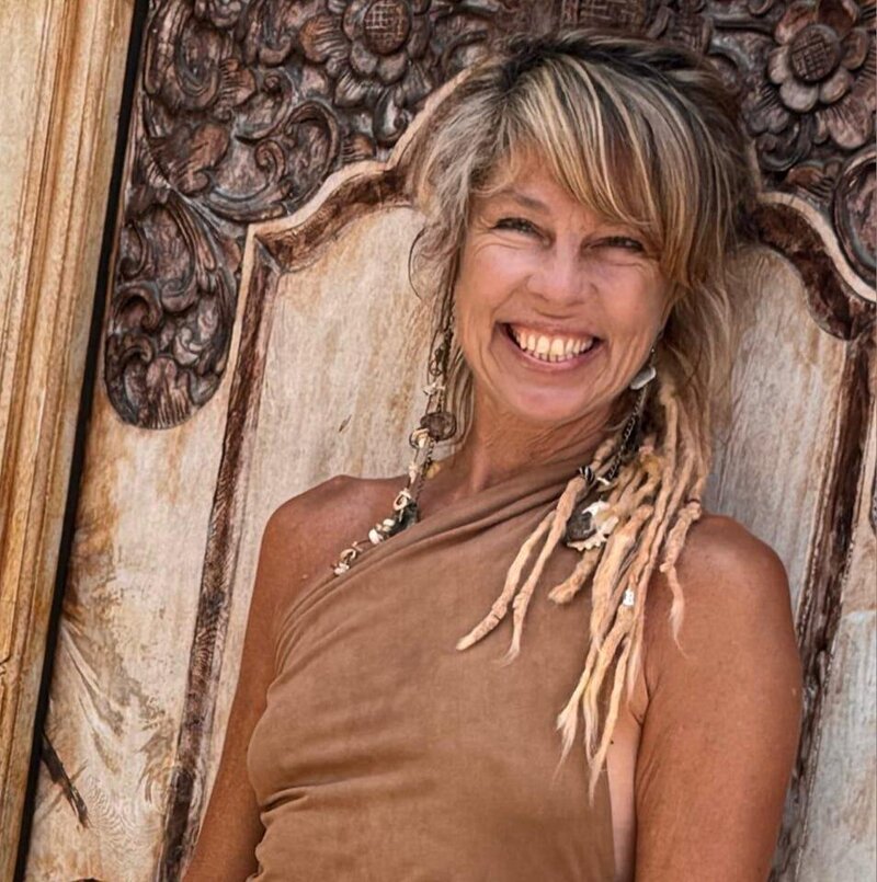 Andrea Binder smiling in natural light, yoga instructor in Sayulita, Mexico, standing against a carved wooden door.