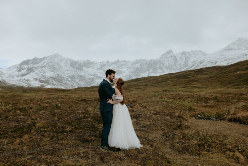A couple standing together holding a bouquet of flowers after their wedding ceremony. 