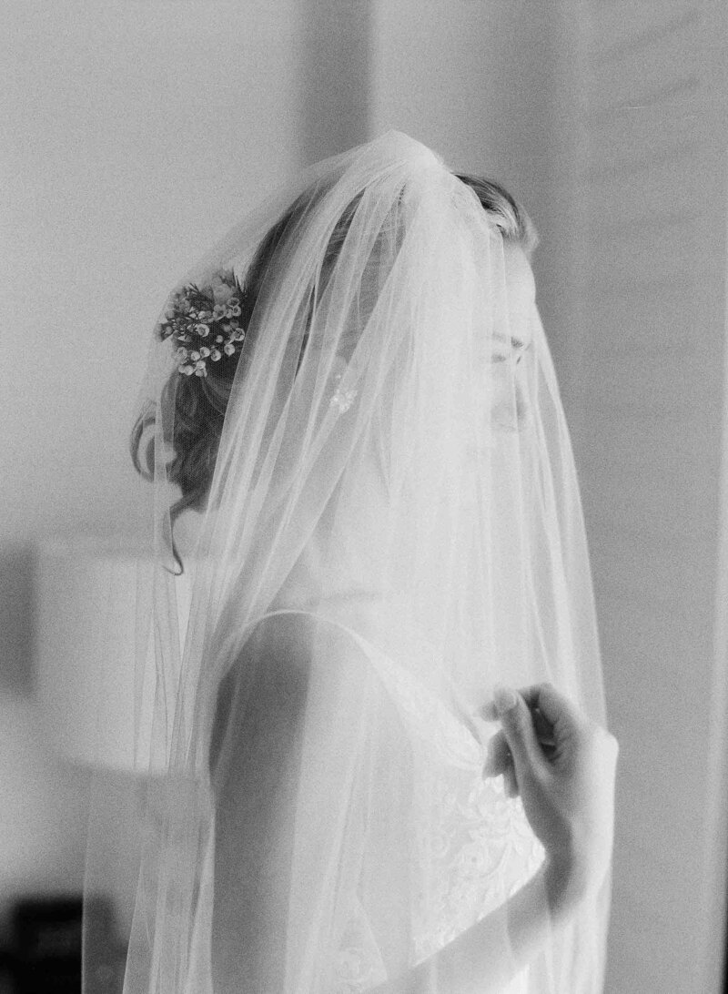 black and white photo of bride with veil over her in hotel room