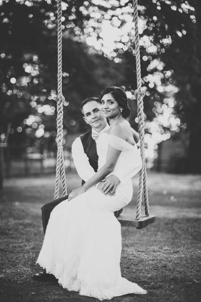A black and white photograph of a newly married couple sat on a rope swing taken by London Wedding Photographer Liberty Pearl