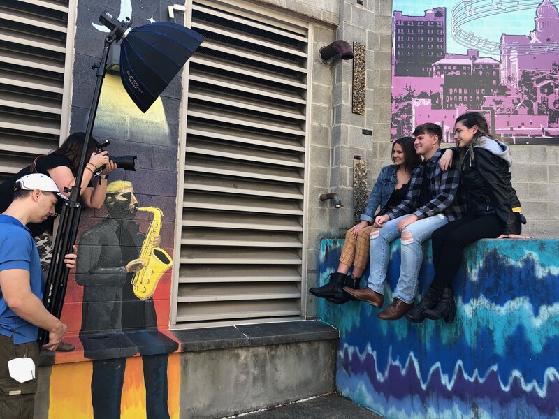 Photo shoot of 2 senior girls and 1 senior guy sitting on graffiti wall