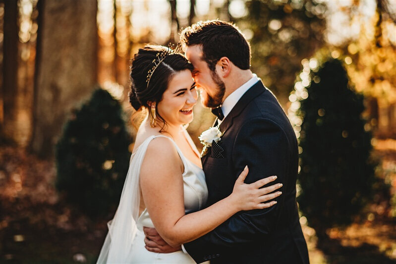 Baltimore photographers captures bridal portraits with groom holding his bride around the waist as she holds his arms and they both laugh in the courtyard