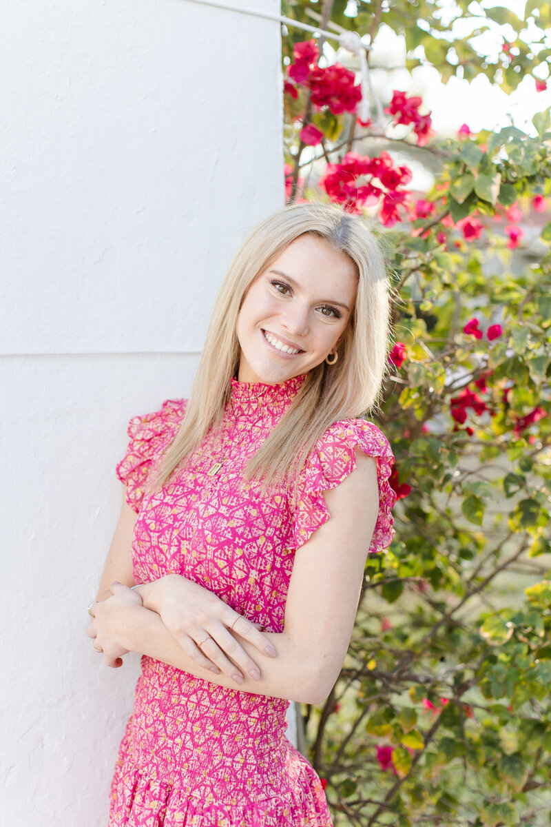 young woman in a pink dress posing by flower bush