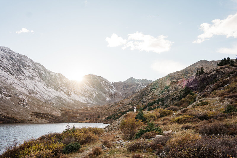 A tiny couple kiss at sunset at a mountain lake in Breckenridge