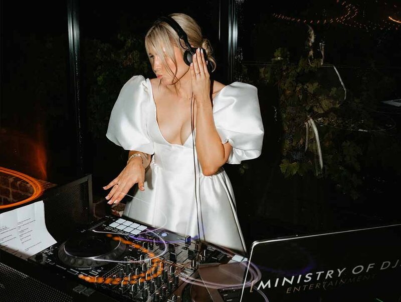 Bride DJ in elegant white dress performing at the decks for Ministry of DJs wedding entertainment